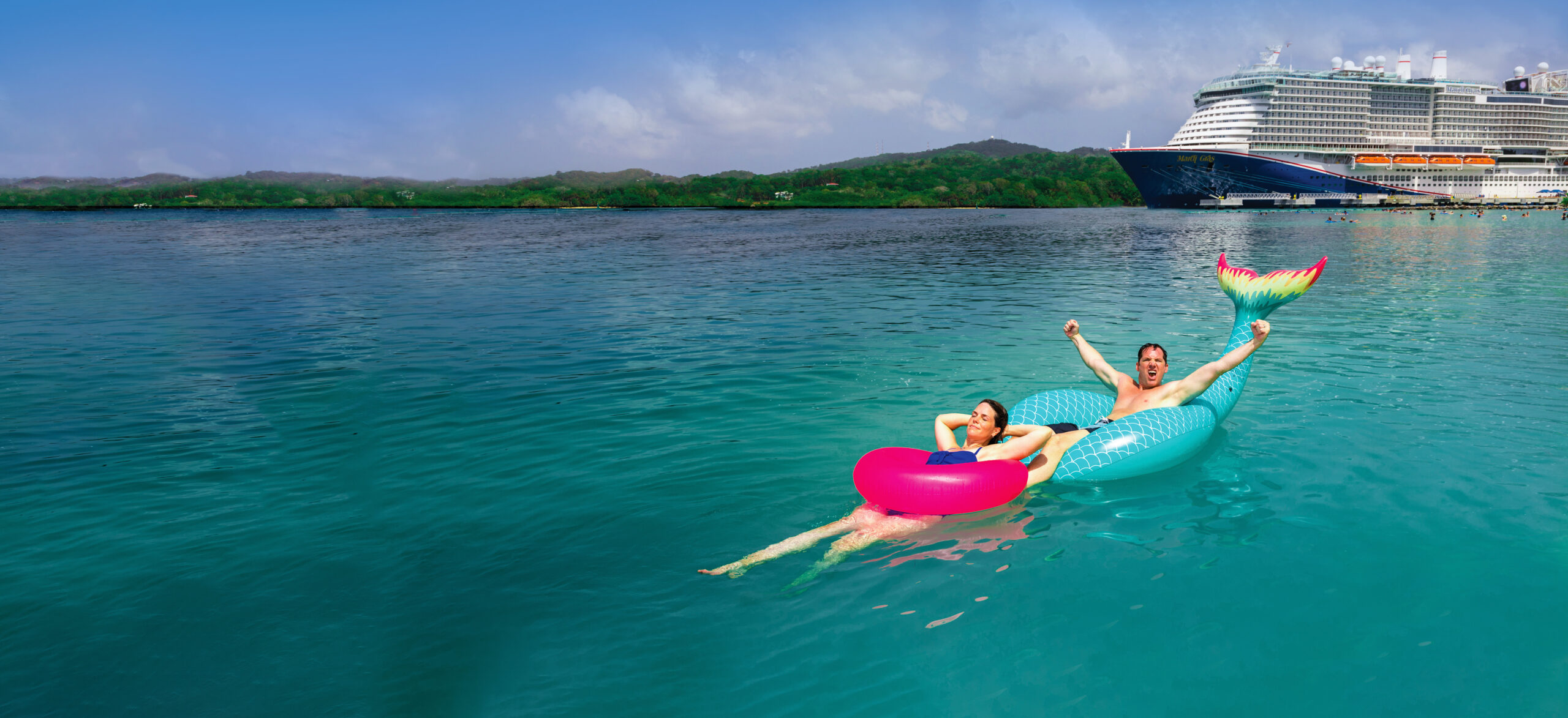 Couple enjoying the sea breeze on the deck of Carnival Mardi Gras at Mahogany Bay.